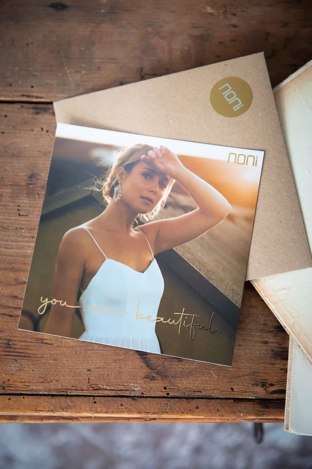 noni-geschenkgutschein-quadratische-postkarte-mit-golddruck image 1